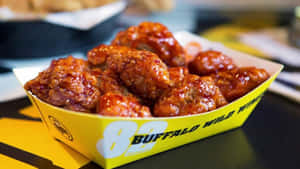 脆皮水牛城雞翼放在黃色的 Buffalo Wild Wings 紙托盤中。