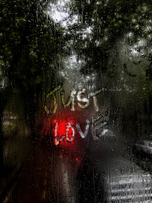 玻璃上的雨滴，發光紅色霓虹文字寫著 just love