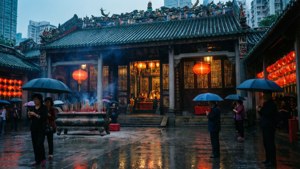 人們撐著傘在雨中於紅燈籠照亮的寺廟祈禱。