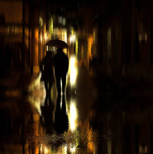 情侶在雨夜的城市街道上撐傘行走，金色倒影。 — 情侶 GIF 壁紙