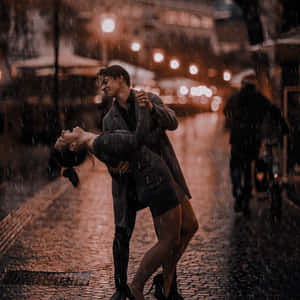 情侶在夜晚城市街道上，在溫暖燈光下於雨中跳舞。 — 可愛情侶 GIF 壁紙