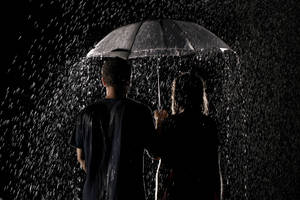 兩人在大雨的夜晚共用一把雨傘。