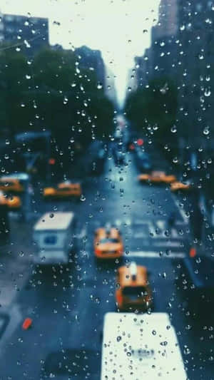 窗戶上的雨滴，可看到黃色的士和城市建築。