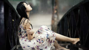 雨中坐在橋欄杆上的花卉連衣裙女子
