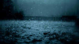 雨滴在暴風雨的天空下濺在潮濕的地面上 — 雨天 壁紙