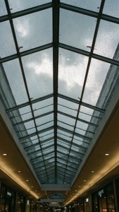 購物中心玻璃天花板上的雨滴，上方可見多雲天空