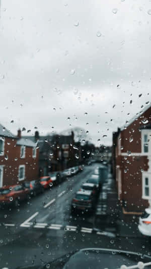 車窗上的雨滴，濕漉漉的街道和磚建築的景色。