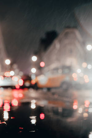 雨滴將城市燈光模糊成發光球體，夜晚在濕漉漉的人行道上。 — 雨天 壁紙