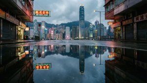 黃昏時雨坑中反射的香港城市景觀，霓虹燈閃爍。 — 暮光 壁紙