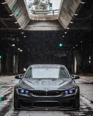 黑色BMW跑車在夜間雨中行駛於高架橋下。