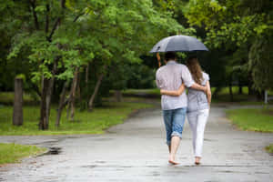 一對情侶赤腳撐傘走在潮濕的公園小徑上。 — 雨 壁紙
