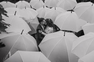 一對情侶在白色雨傘的田野中黑白接吻。