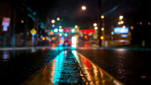 城市街道上的夜雨，模糊的交通燈光反射在濕漉漉的路面上。 — 暗夜城市 壁紙