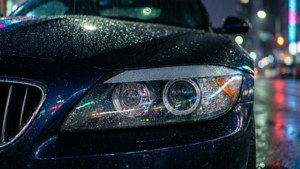 雨濕的汽車頭燈在夜間反射霓虹城市燈光。