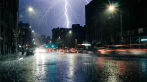 雷雨夜的城市街道，閃電和濕漉漉的人行道反射燈光。