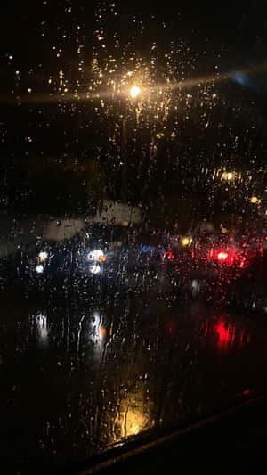 夜間車窗上的雨滴，反射路燈和車尾燈。