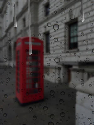窗戶上的雨滴，外面可見的紅色電話亭。