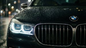 黑色寶馬汽車前格柵和頭燈在雨中發光夜間城市場景