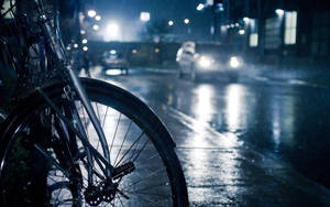 單車停泊在夜晚濕滑的街道上，車燈在雨中反射。 — 夜景城市 壁紙