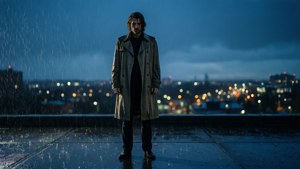 穿著風衣的男子站在下雨的屋頂上，俯瞰夜晚的城市燈光。