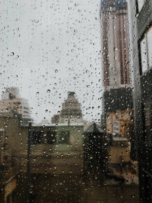 窗戶上的雨滴，背後是模糊的城市景色。