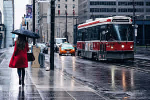 穿紅色外套的女人在雨中行走，電車駛過 — 雨天 壁紙
