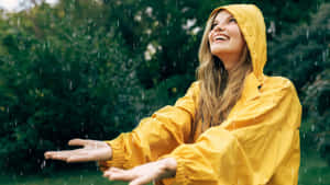 身穿黃色雨衣的女性在雨林中張開雙臂微笑