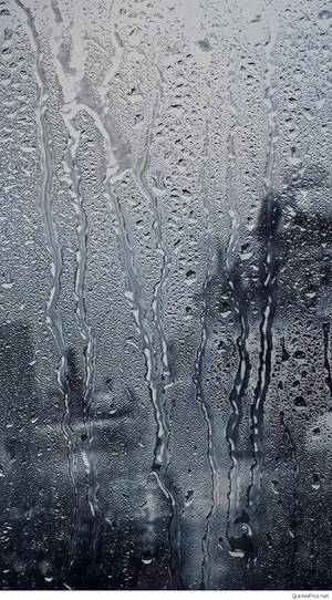 雨滴在玻璃窗上滑落，背景模糊。