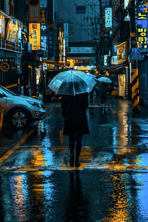 夜晚在雨中霓虹燈照亮的城市街道上，一個人獨自撐傘行走。 — 雨天 壁紙