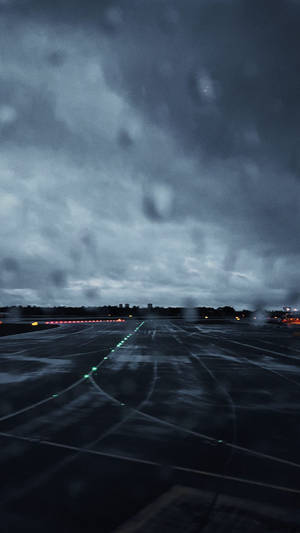 雨滴模糊了黑暗的機場跑道，在暴風雨的天空下，燈光閃爍發光。 — 雨天 壁紙