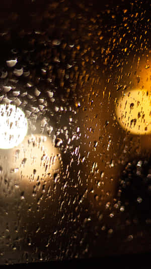 夜晚，車窗上的雨滴與模糊的街燈溫暖地發光。