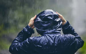穿著深藍色雨衣的人在暴風雨中拉起兜帽。 — 雨天 壁紙