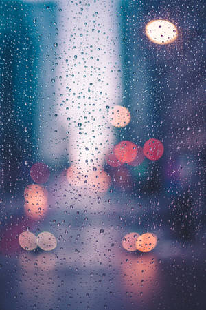 窗戶上的雨滴，夜晚中模糊的城市燈光閃爍。 — 雨天 壁紙