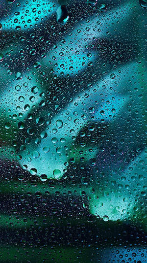 窗戶上的雨滴顯示出藍綠色和綠色的天空 — 雨 壁紙