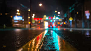 雨夜街道，模糊燈光映照在濕潤路面上。