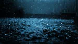 雨滴在深藍色夜空下的潮濕表面上飛濺。 — 雨天 壁紙