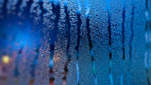 雨滴沿玻璃窗流下，背後有模糊的城市燈光。 — 視窗 壁紙
