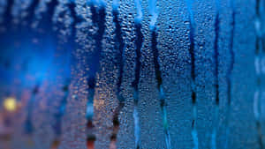 雨滴沿玻璃窗流下，背後是模糊的城市燈光。 — 雨天 壁紙