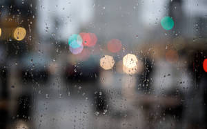 窗上的雨滴，背後是模糊的城市燈光。 — 雨天 壁紙