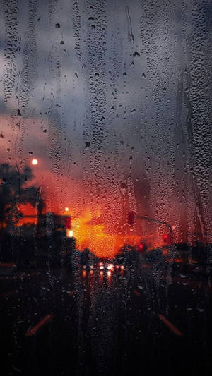 車窗上的雨滴，背後模糊的橙色夕陽交通燈。 — 落雨 壁紙