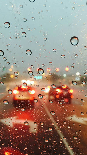 夜間汽車窗戶上的雨滴與模糊的城市燈光。