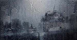 雨滴沿玻璃窗流下，模糊的城市景觀。