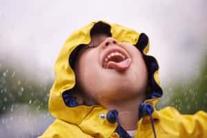 穿著黃色雨衣的孩子在雨中伸出舌頭大笑