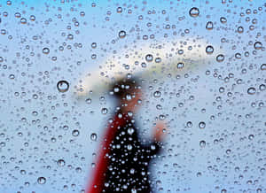 透過濺滿雨水的窗戶看到模糊的人撐著雨傘