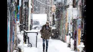 人在雪中走過佈滿塗鴉的都市小巷。