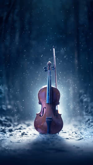 小提琴和琴弓在夜間藍色森林下的雪中站立。