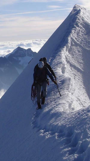 兩名登山者在雲上攀登積雪山脊