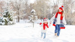 母親和女兒在陽光明媚的冬日裡在雪地公園玩耍。 — 跑步 壁紙