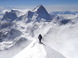 登山者在雪脊上，雲海之上，遠方有山峰