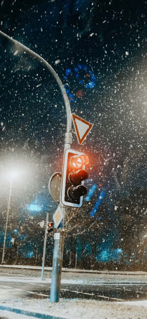 紅色交通燈在夜間城市街道的飄雪中發光。